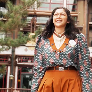 female dispatch greeter in costume, smiling in front of a Disney resort